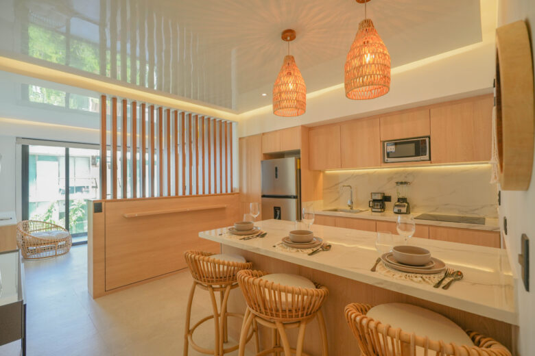 Cocina de diseño contemporáneo con acabados en madera y mármol, iluminación cálida y detalles naturales, dentro de un desarrollo con departamentos en venta en Playa del Carmen que combinan lujo, funcionalidad y estilo caribeño.