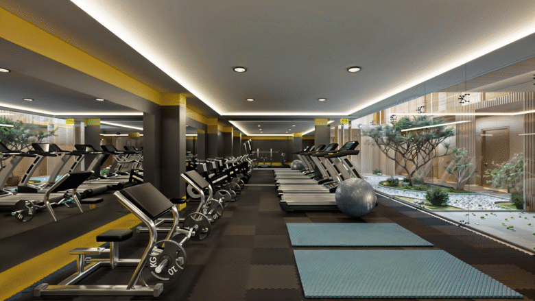 Gimnasio de Macondo Corazón en Playa del Carmen, completamente equipado con diseño interior moderno, iluminación indirecta y ventanales que dan a un jardín interior con árboles y vegetación. Un espacio pensado para el equilibrio y la salud dentro de los departamentos en venta en Playa del Carmen.